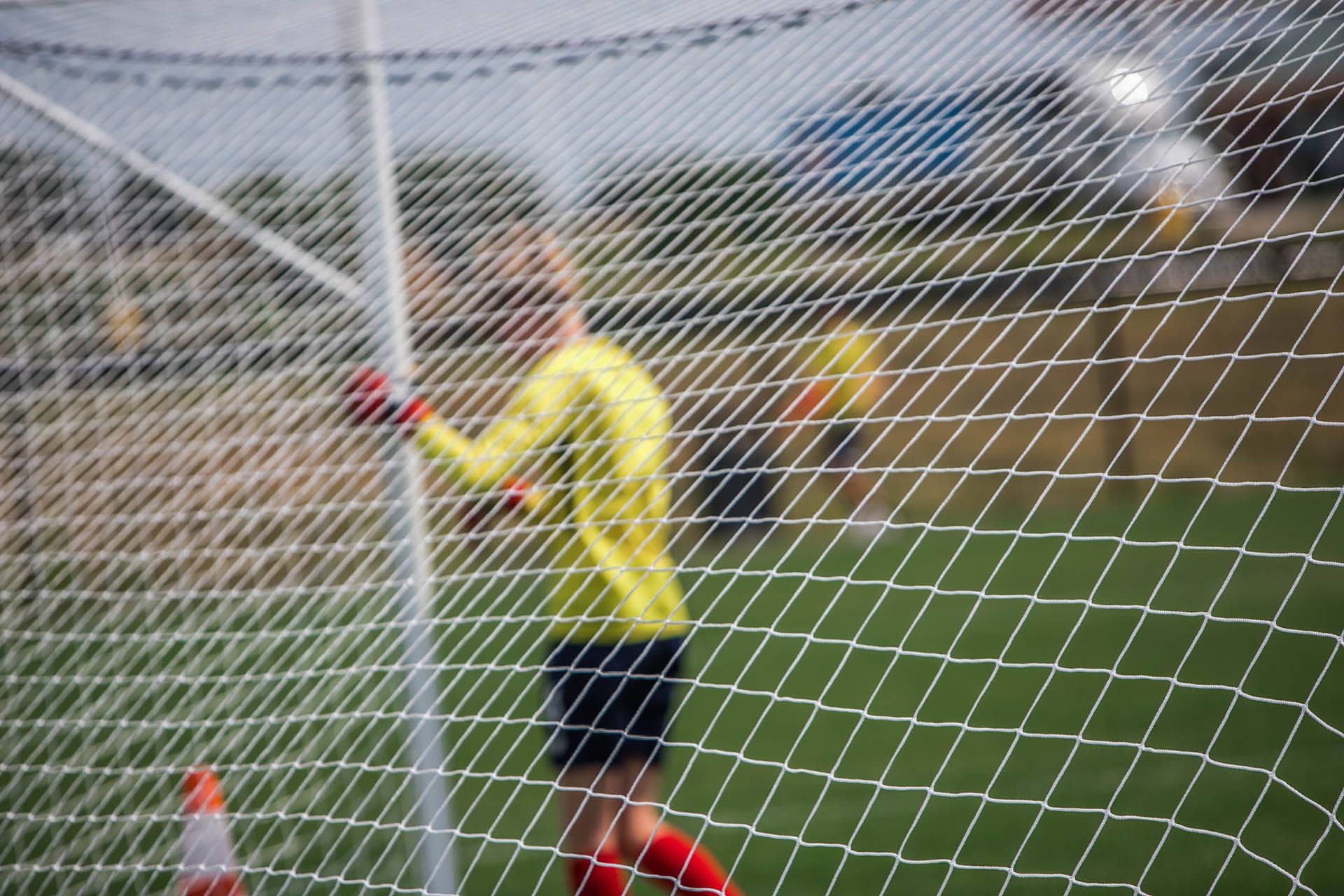 Soccer net with goalie in background.