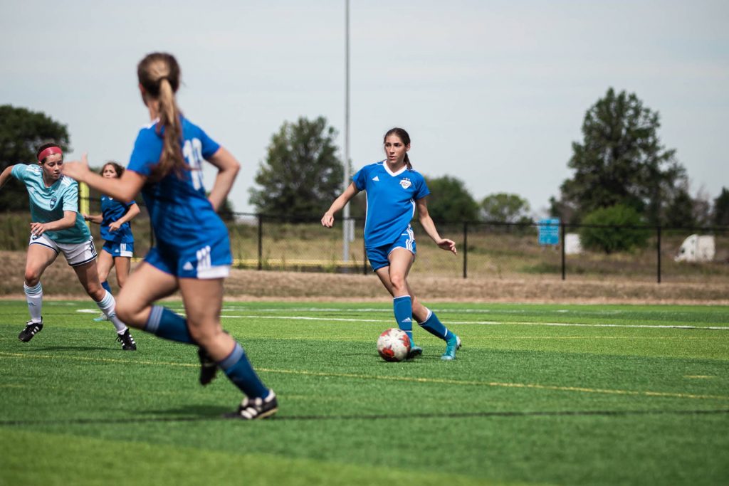 Girls in uniform playing soccer.