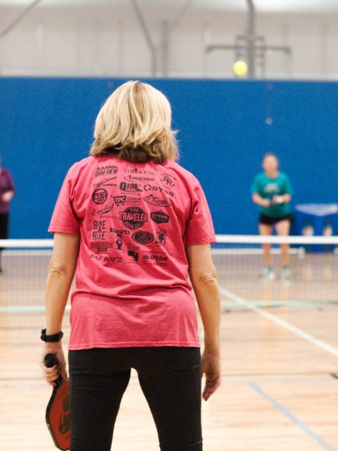 Older woman getting ready to receive pickleball.